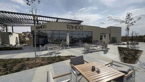 An outdoor seating area with tables and chairs, a pergola, and a building with 'TEMPO' signage. - Stylish 3BR Serviced Aprt Pool View Sodic Villette (Cairo Governorate)