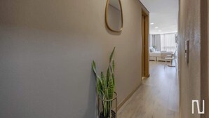 A hallway with a potted plant, a mirror, and a view into a living area with a sofa and a table. - NOK 1BR Loft Serene in Usaquen (Bogotá)