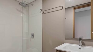A modern bathroom with a glass shower enclosure, a white toilet, and a wooden vanity with a mirror. - NOK 1BR Loft Serene in Usaquen (Bogotá)