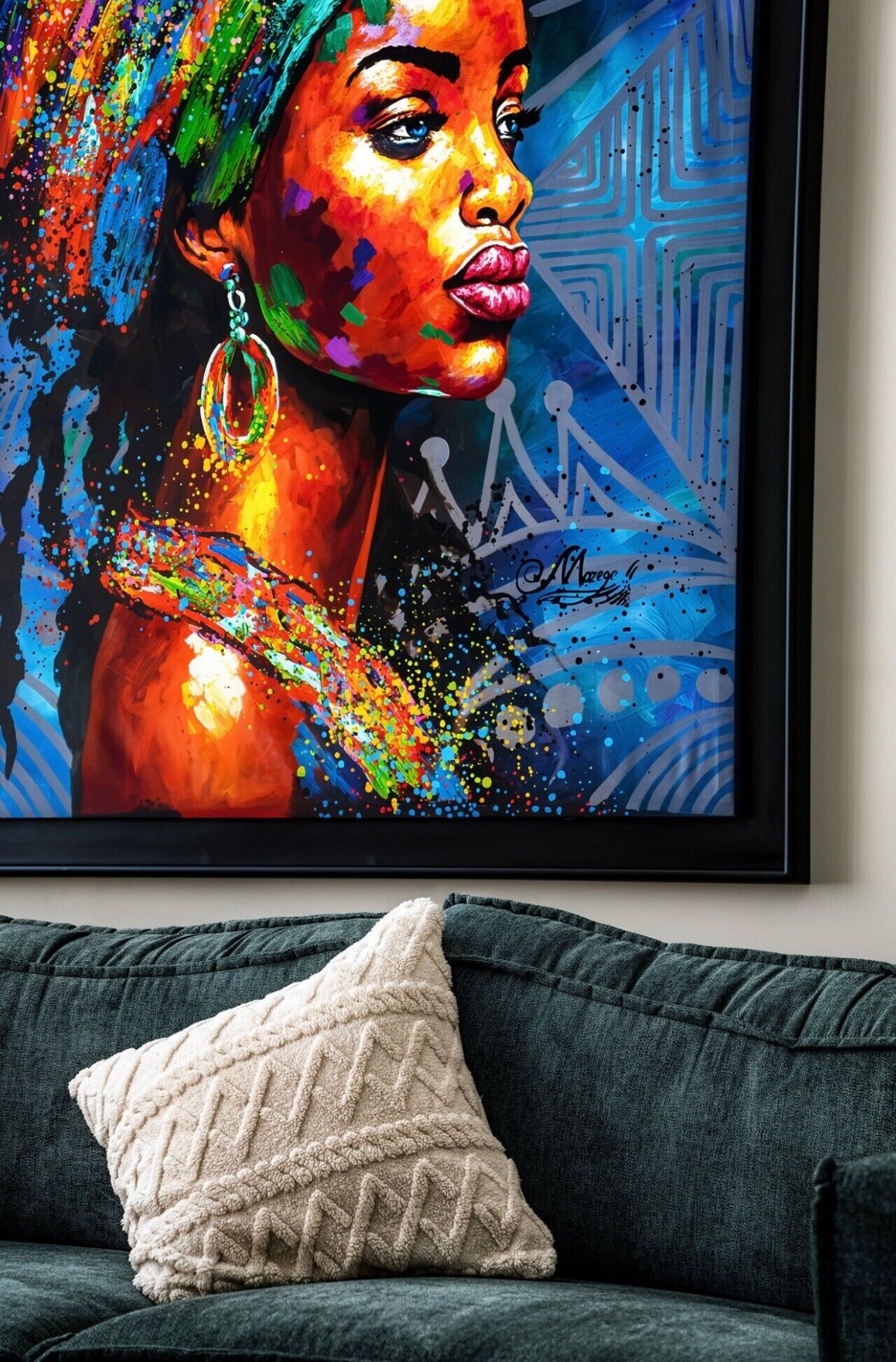 Ein gerahmtes Kunstwerk an einer Wand über einem dunkelgrünen Sofa mit einem weißen, strukturierten Kissen.