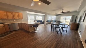 A modern kitchen with wooden cabinets, a dining area with a table and chairs, and a ceiling fan. - Boater & Beach Lover’s Retreat (Manahawkin)