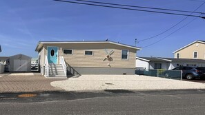 A single-story house with a blue door, a small porch, and a garage. - Boater & Beach Lover’s Retreat (Manahawkin)