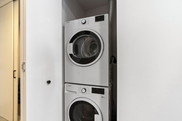 A compact, modern laundry room with two stacked front-loading washing machines. - 121 Ne Miami Living - We Host (Miami)