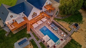 A large house with a swimming pool, outdoor seating, and a covered patio area.