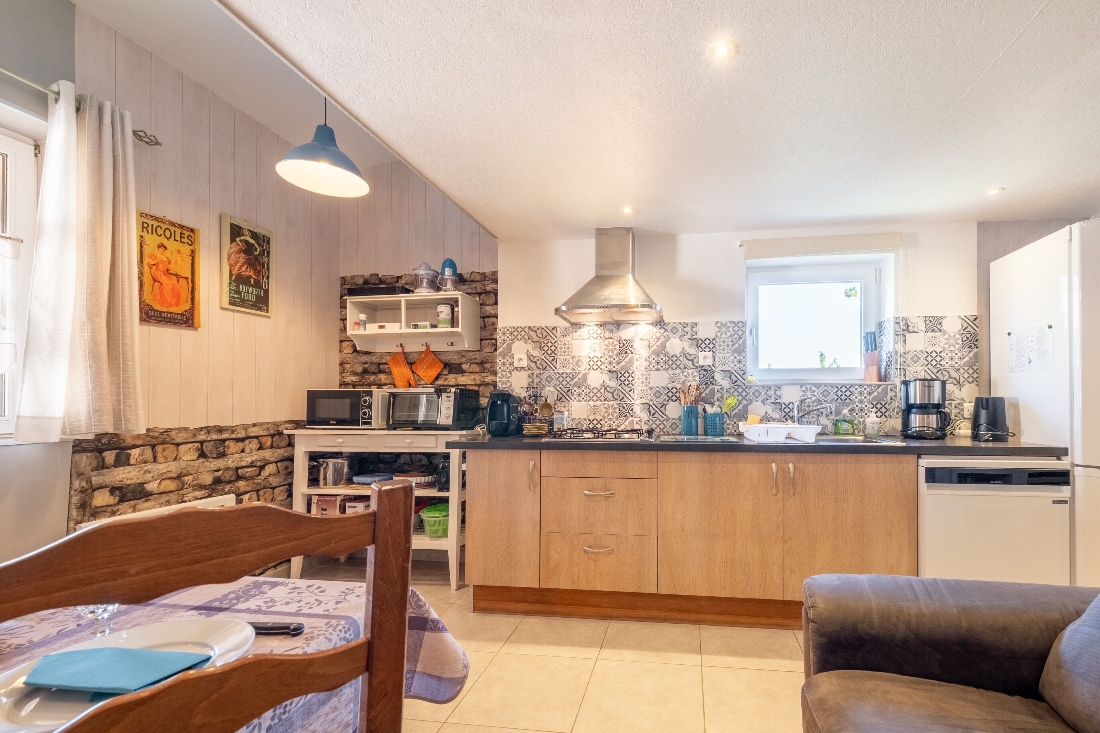 A compact kitchen with wooden cabinets, a microwave, a coffee maker, and a patterned backsplash.
