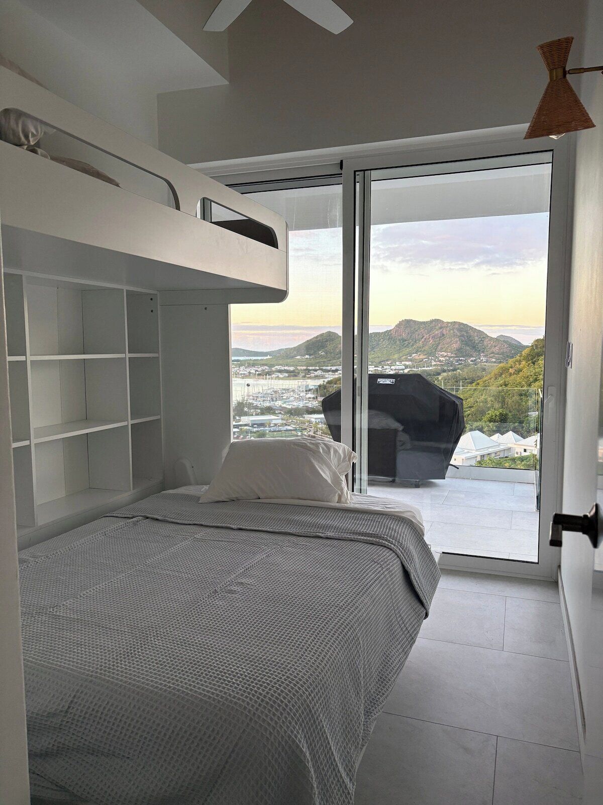 Una camera da letto moderna con un letto a castello, un'ampia finestra e vista su un paesaggio montuoso.