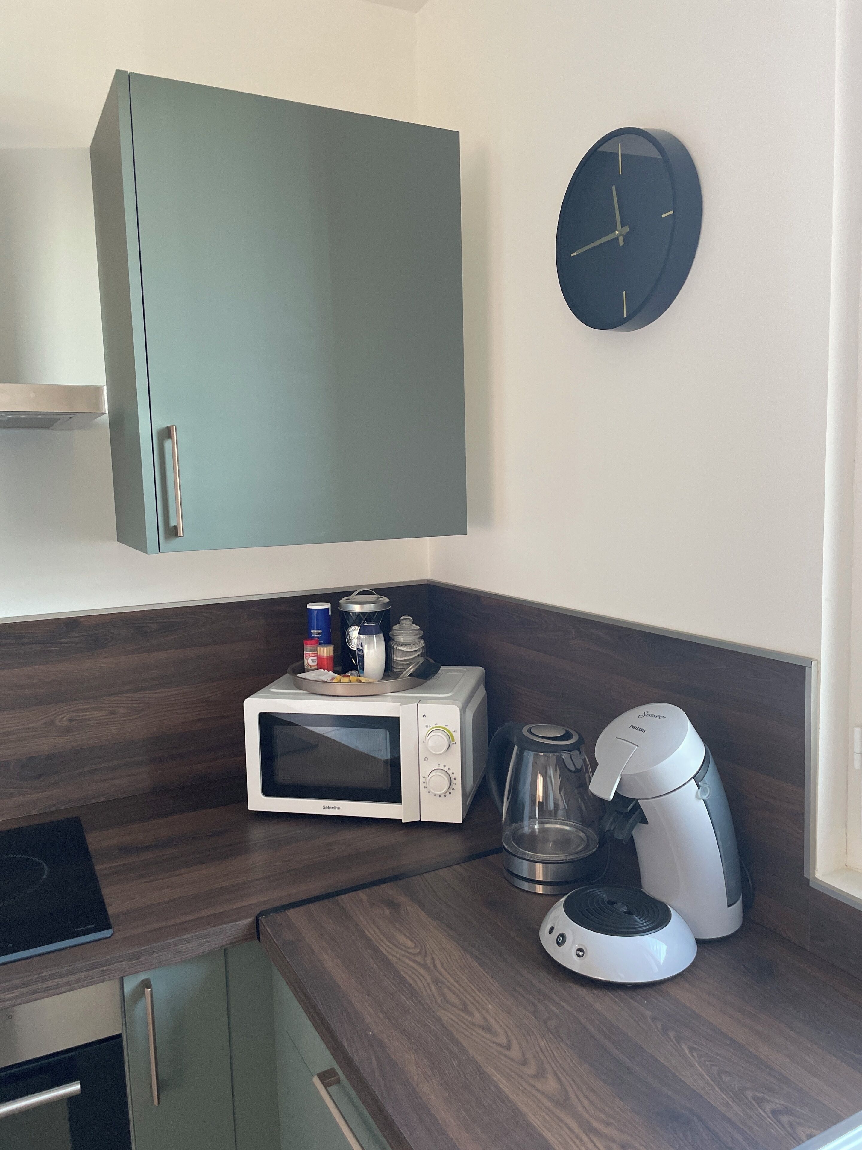 A kitchen with a microwave, coffee maker, and cabinets.