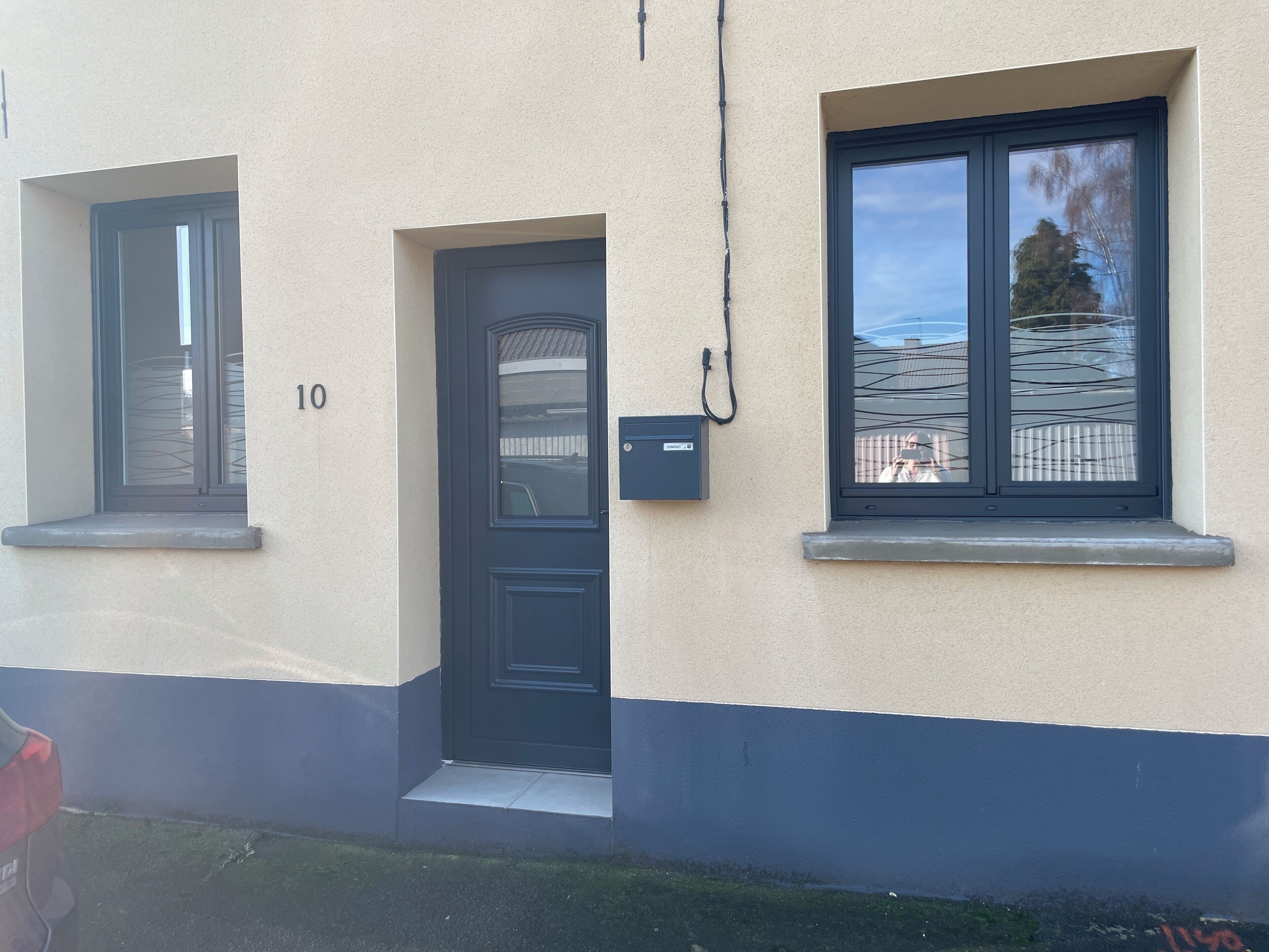 A building with a black door, a window, and a mailbox.