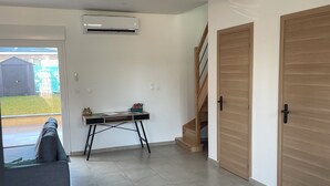 Un vaste espace de vie comprenant un canapé gris, une petite table et un escalier menant à un autre niveau.