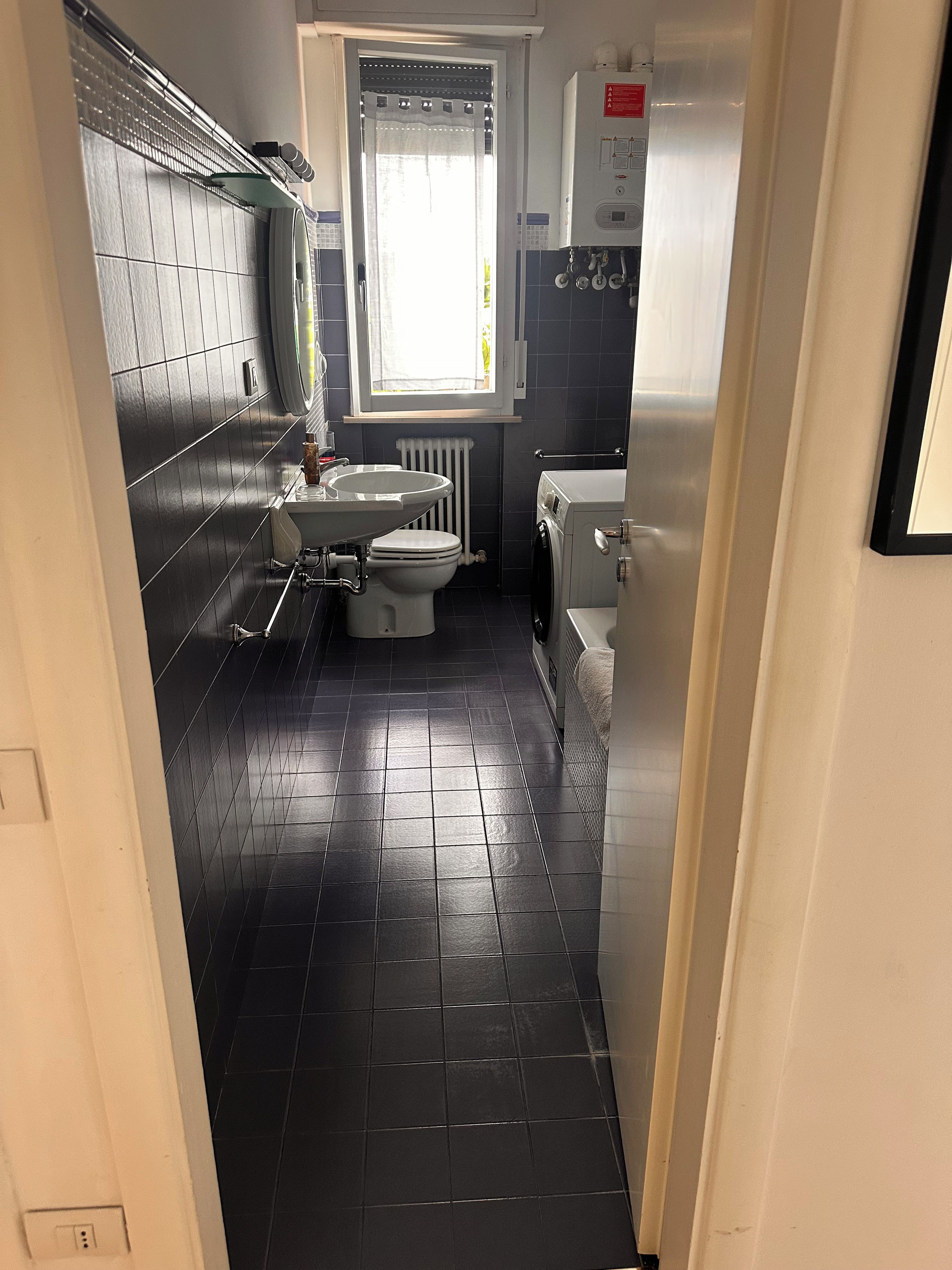A compact bathroom with a toilet, sink, and washing machine.