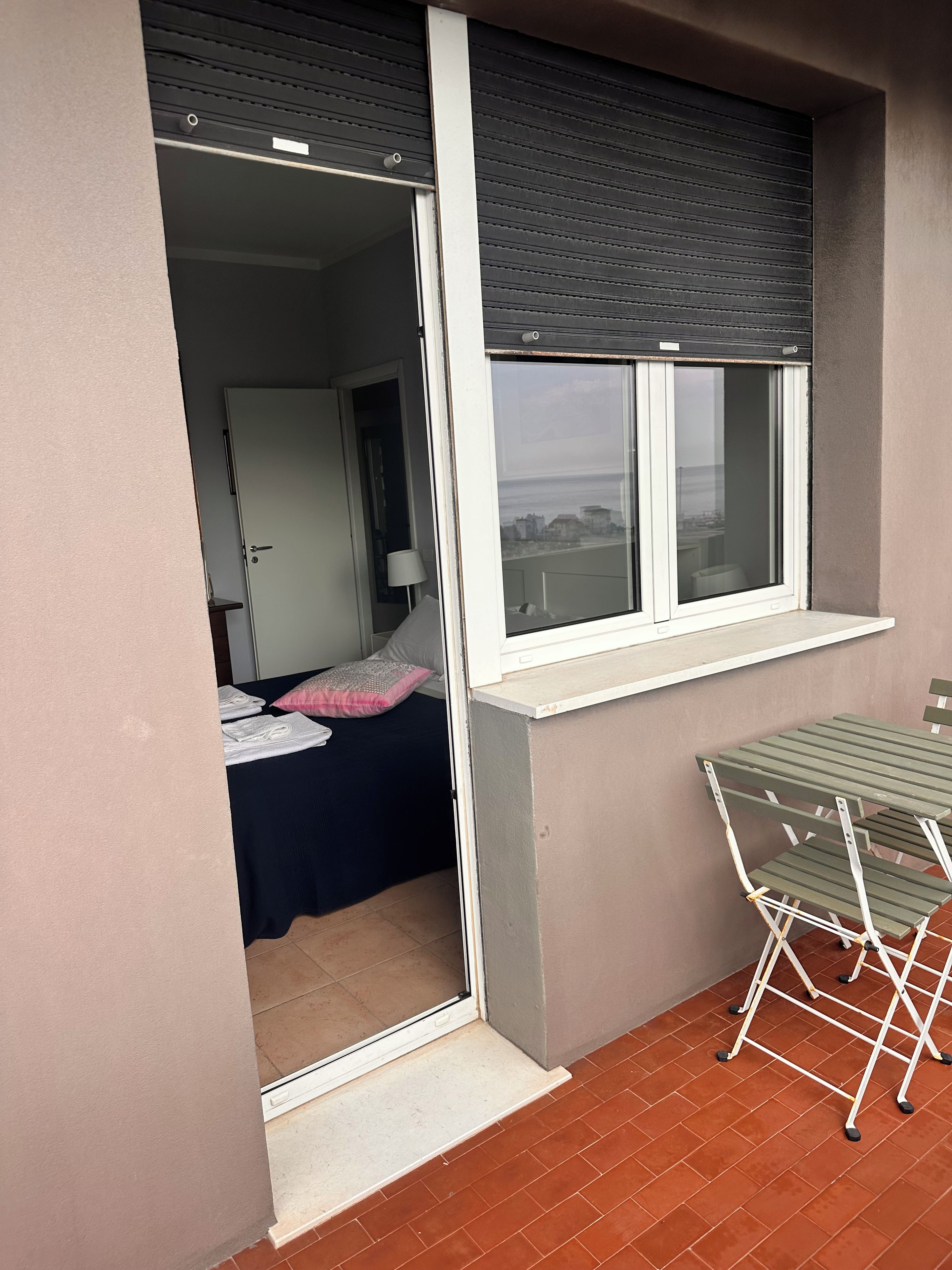 A room with a bed, a table, and a window with a blind.