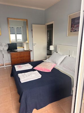 A hotel room with a bed, a desk with a computer, a mirror, and a door leading to another room. - Waterfront apartment with breathtaking views in a very central location. (Pesaro)