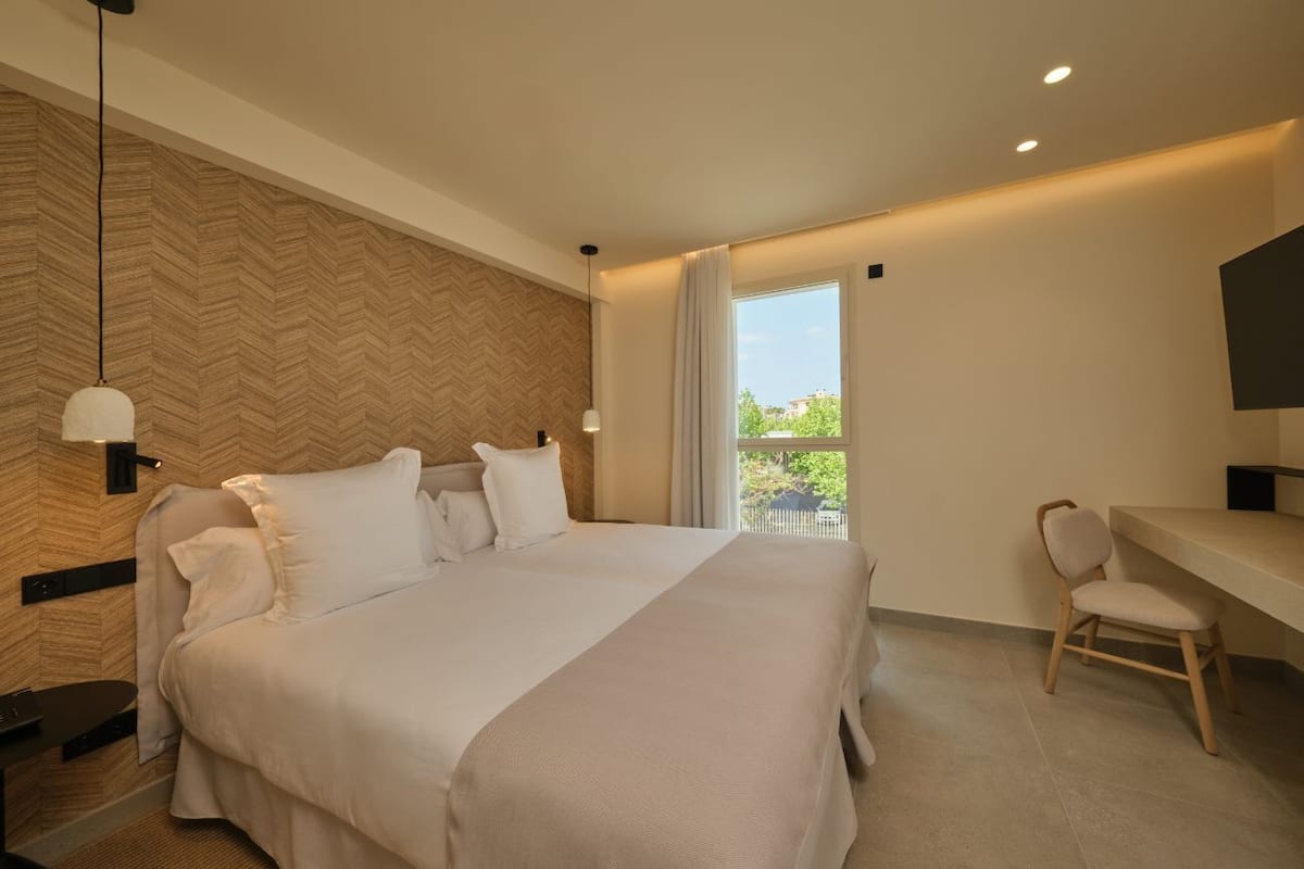 Ein modernes Hotelzimmer mit einem großen Bett, einem Schreibtisch und Blick auf Grünflächen.