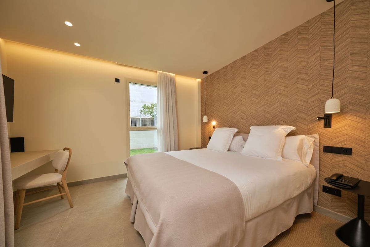 Ein modernes Hotelzimmer mit einem großen Bett, einem Schreibtisch und einem Stuhl.