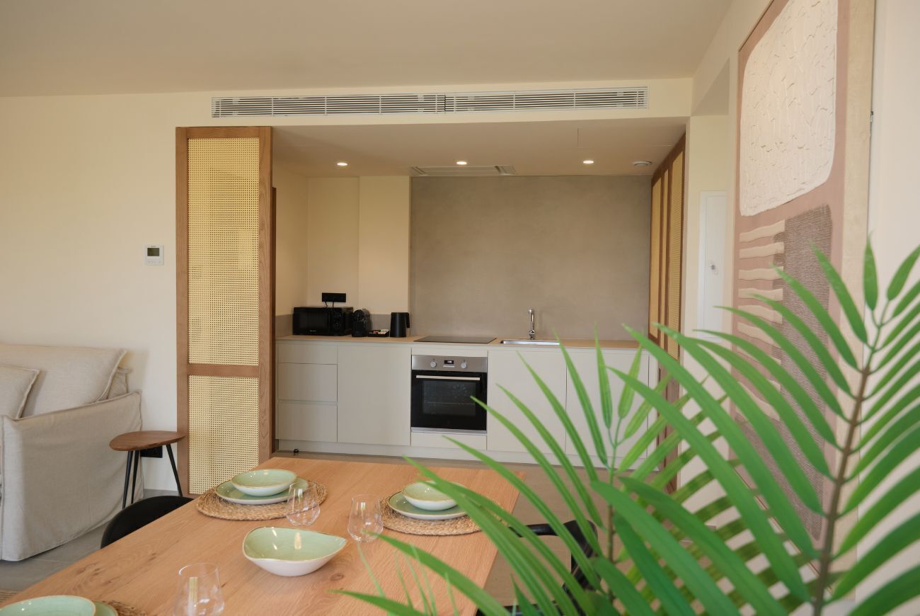 A modern kitchen with a dining area, a sofa, and a plant.