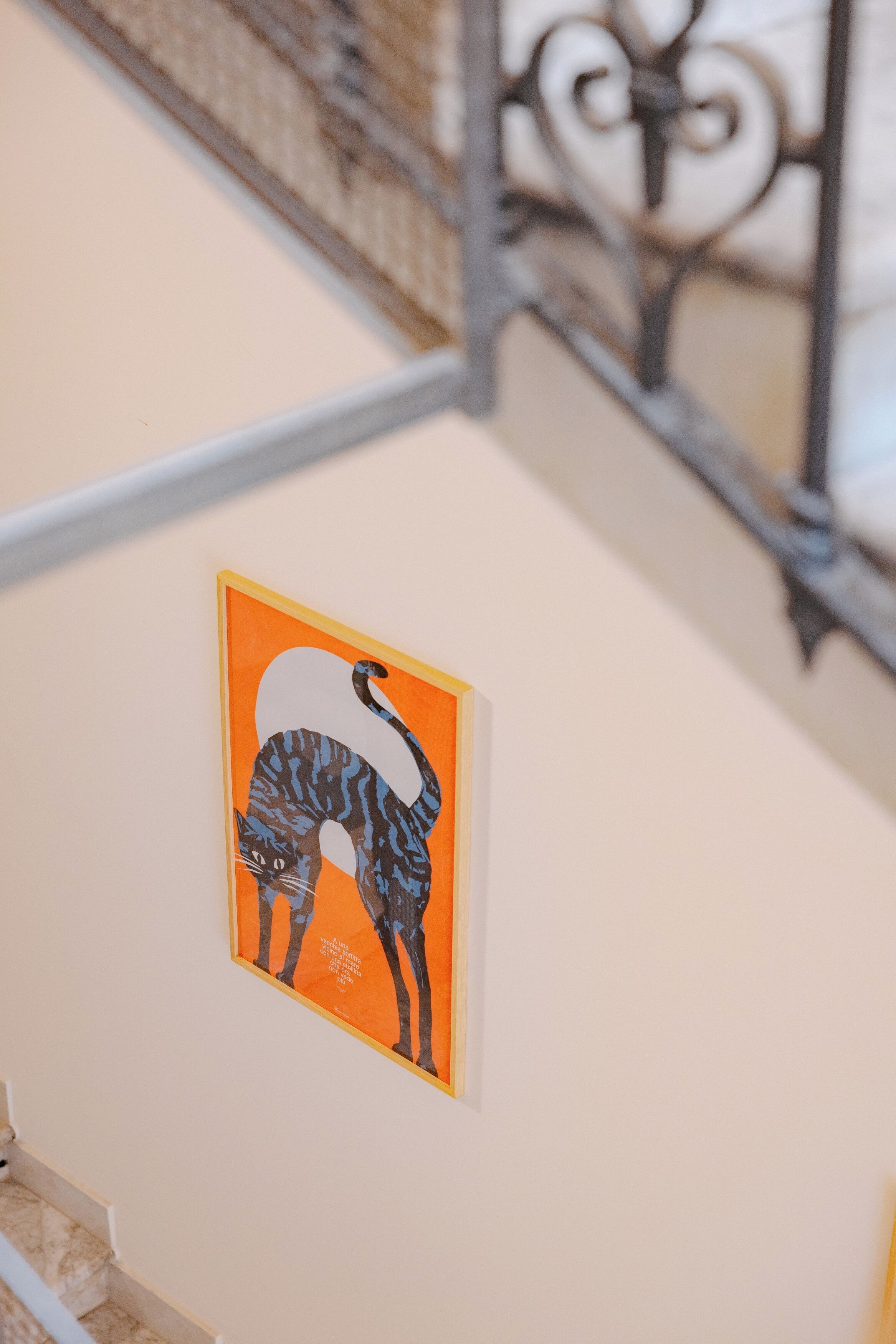 Una escala amb barana metàl·lica i una obra d'art amb un animal estilizado penjada a la paret.