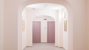 Een hal met een gewelfde plafond, twee deuren en beelde kunst aan de muren.
