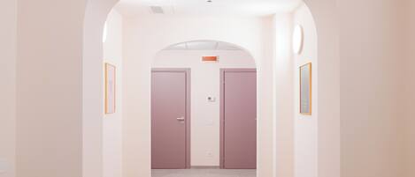 Um corredor com teto em arco, duas portas e quadros nas paredes.