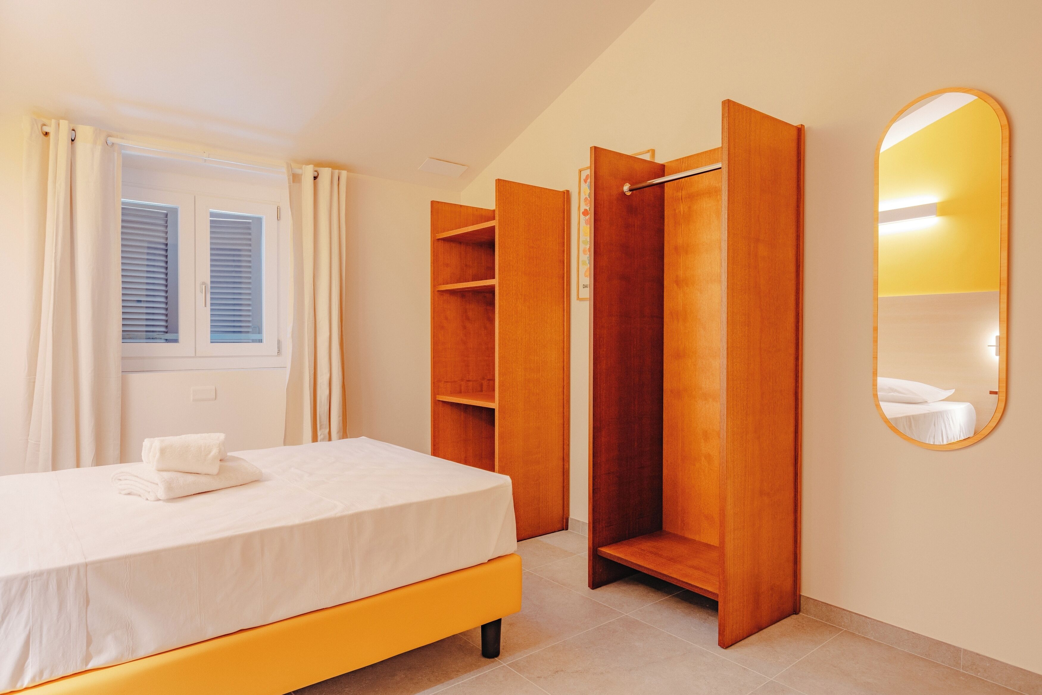 A bedroom with a bed, wooden wardrobe, and a mirror.