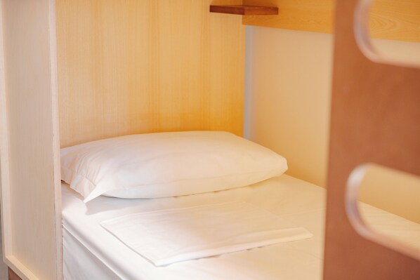 A single bed with white bedding, a wooden headboard, and a door frame. - Tomato Urban Retreat Ostello della gioventu (Rome)