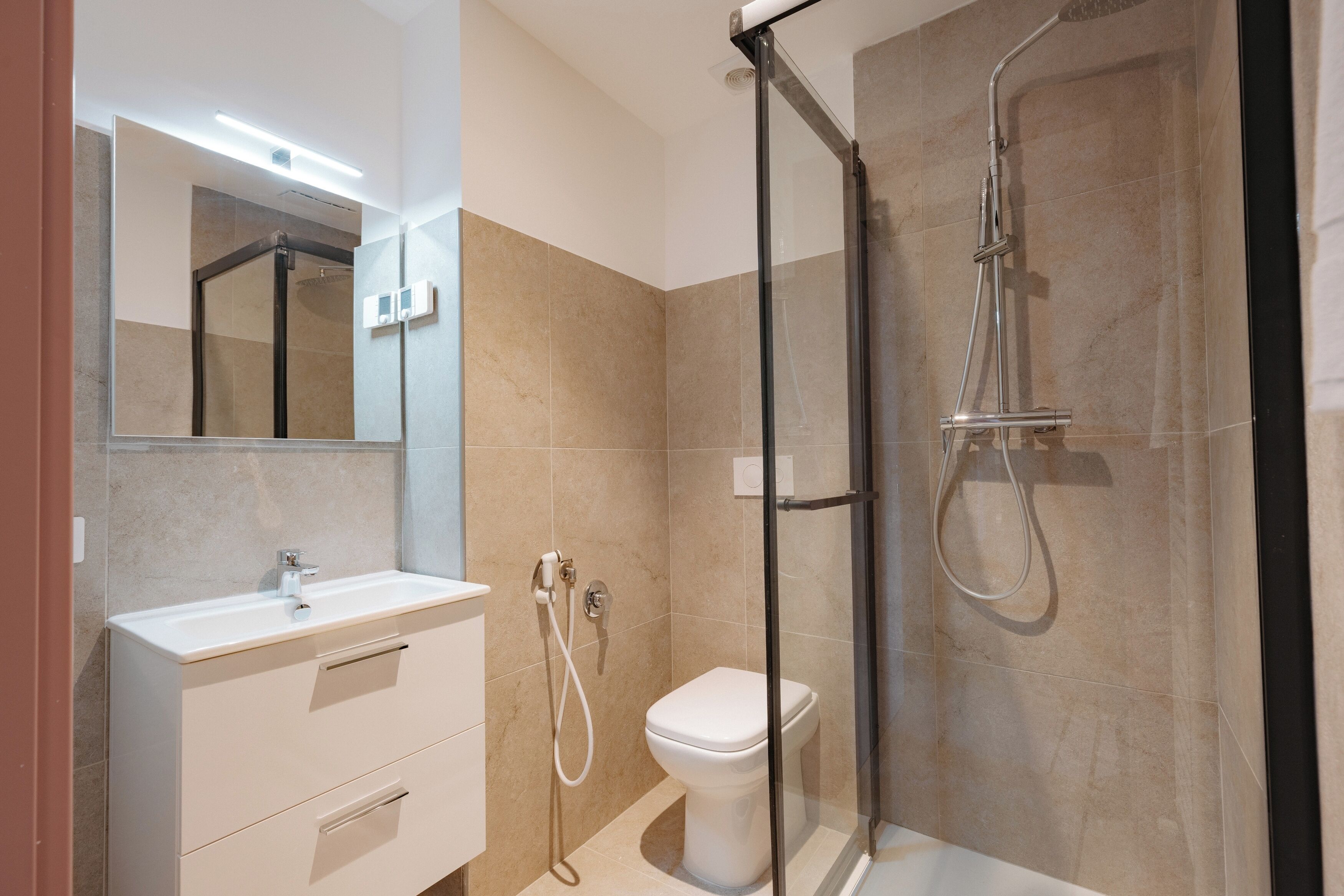 A modern bathroom with a glass-enclosed shower, a white sink, and a toilet.