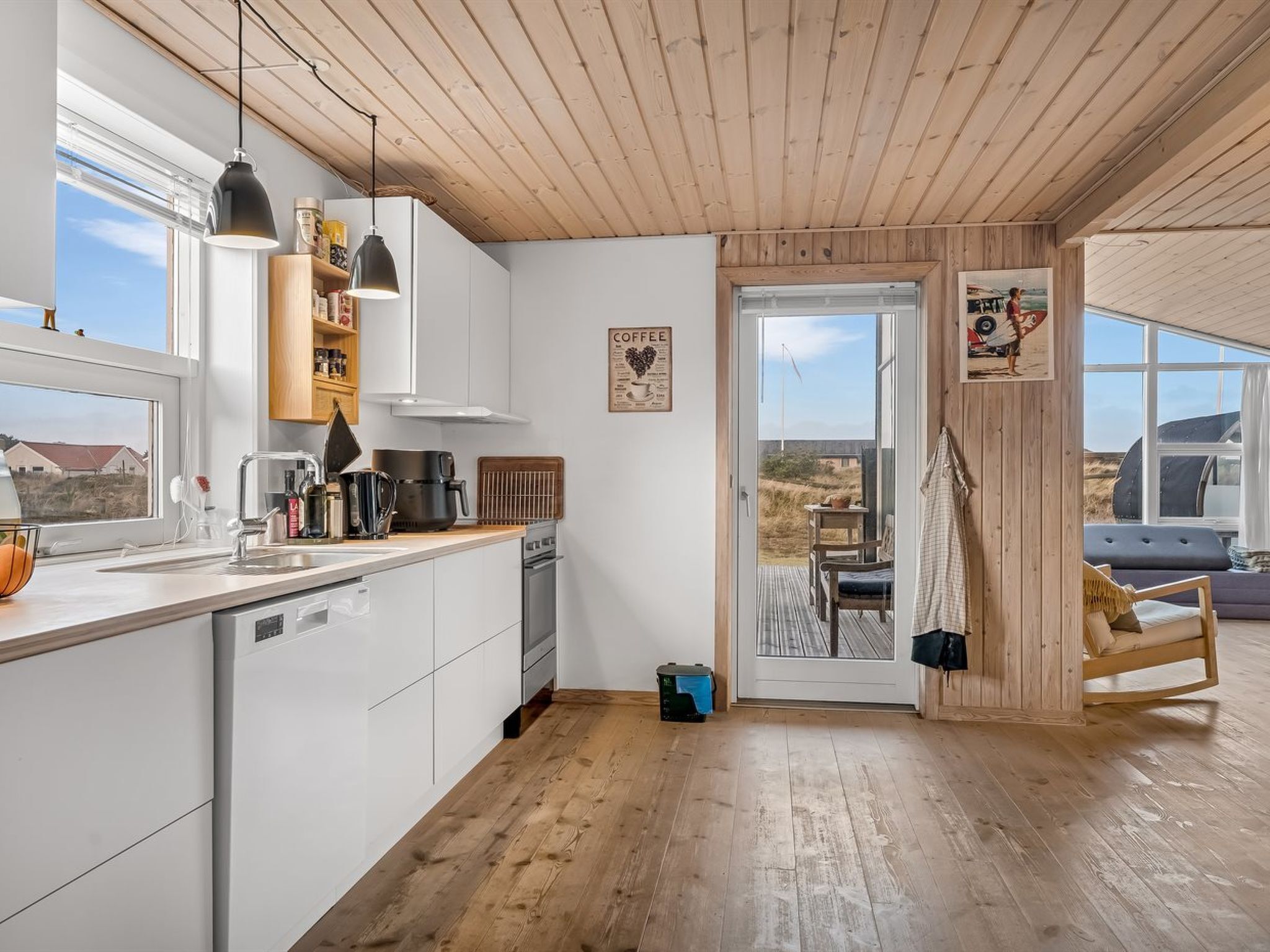 Eine moderne Küche mit weißen Schränken, einer Holzbalkendecke und einem großen Fenster.