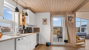 Een moderne keuken met witte kastjes, een houten plafond en een groot raam.