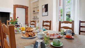 Una mesa de desayuno con diversas comidas, una jarrón, tazas y una tetera.