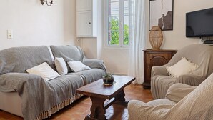Una sala de estar con un sofá, un sillón, una mesa de centro de madera y un televisor.