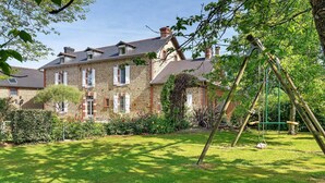 Un bâtiment en pierre avec un jardin et une balançoire.