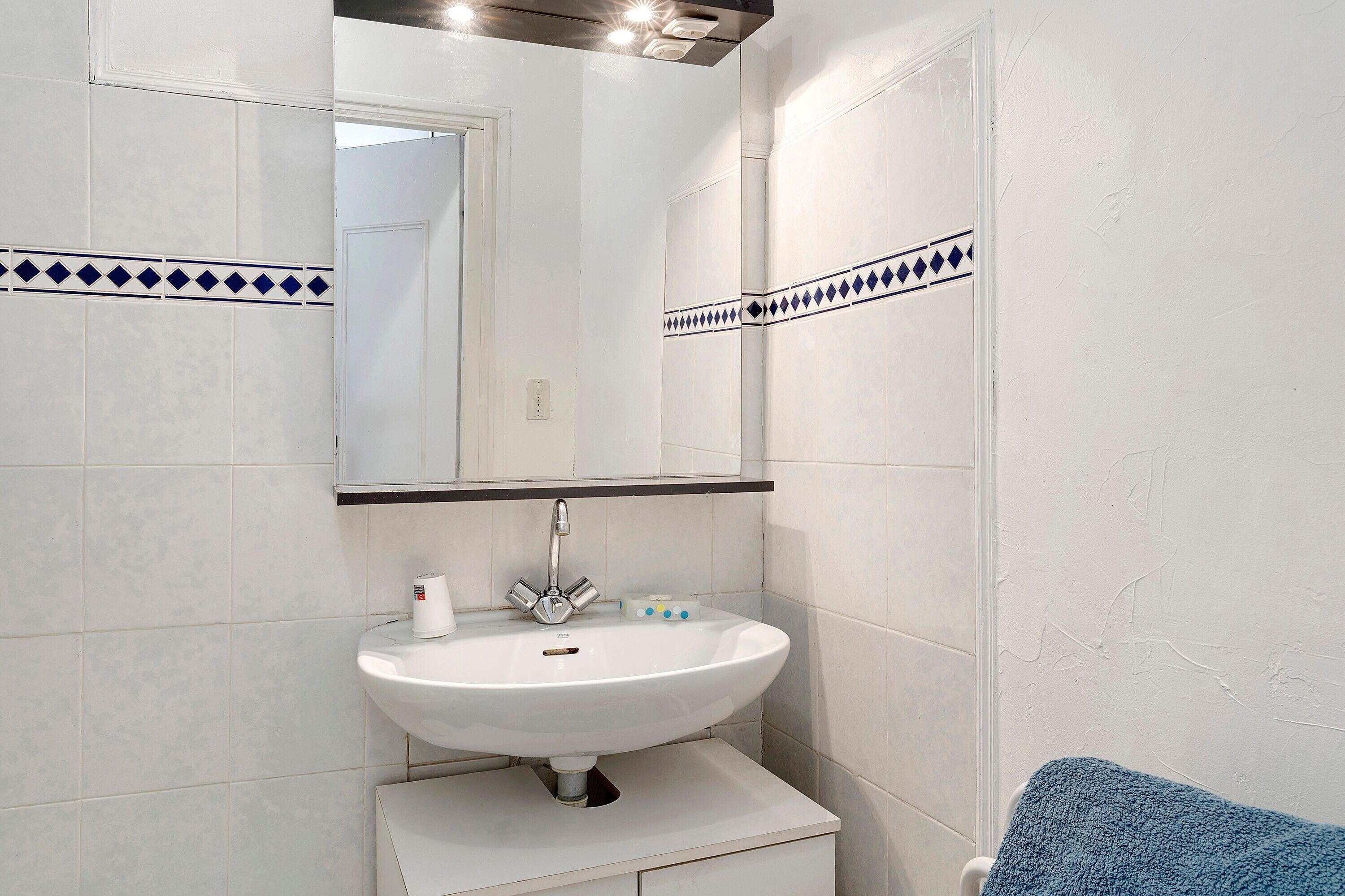 A bathroom with a white sink, mirror, and blue towel.