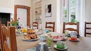 Una mesa de desayuno con diversas comidas, una jarrón, tazas y una tetera.