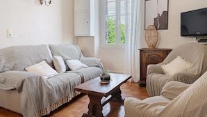 Una sala de estar con un sofá, un sillón, una mesa de centro de madera y un televisor.