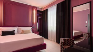 Ein modernes Hotelzimmer mit einem großen Bett, einem kleinen Schreibtisch und einem Spiegel.