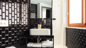 Une salle de bain moderne avec un mur recouvert de carreaux noirs et blancs, un lavabo blanc et un miroir au-dessus.