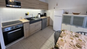 A modern kitchen with a microwave, stove, sink, and refrigerator. There is a dining table with chairs and a decorative bowl on the counter. - Port Fréjus LE NAUTICA, 2/3-bedroom apartment, sleeps 5, close to beaches and amenities, large balcony, air conditioning, Wi-Fi and garage (Fréjus)