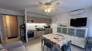 A compact kitchen with a dining area, a ceiling fan, a microwave, and a television. - Port Fréjus LE NAUTICA, 2/3-bedroom apartment, sleeps 5, close to beaches and amenities, large balcony, air conditioning, Wi-Fi and garage (Fréjus)