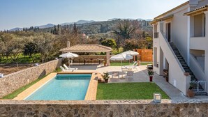Ein Poolbereich mit Pergola, Liegestühlen und Blick auf die Landschaft.