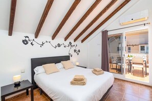 Ein Schlafzimmer mit einem Bett, einem Nachttisch, einer Lampe, einer Wanddekoration und Blick auf eine Terrasse.