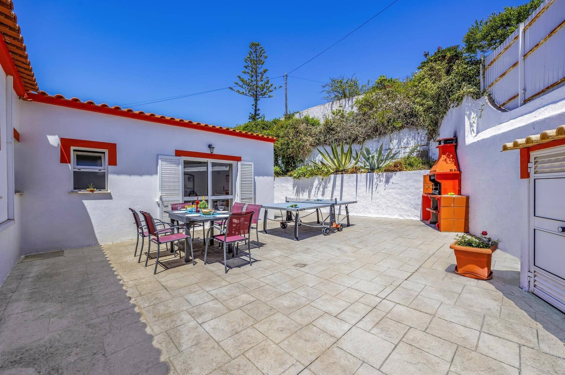 Un espace patio avec une table et des chaises, un barbecue et une petite fenêtre.