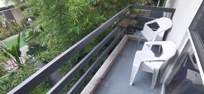 A balcony with two white plastic chairs, a small table, and a railing.