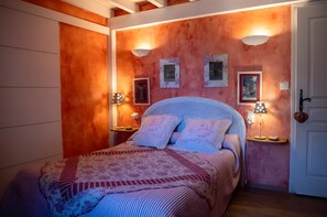 Une chambre à coucher avec un lit, deux lampes fixées au mur et des tableaux encadrés accrochés au mur.
