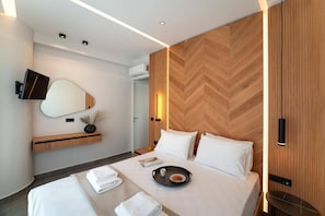 Ein modernes Hotelzimmer mit einem großen Bett, Nachttischen, einem Wand-Fernseher und einer Wandverkleidung aus Fischgrätparkett.
