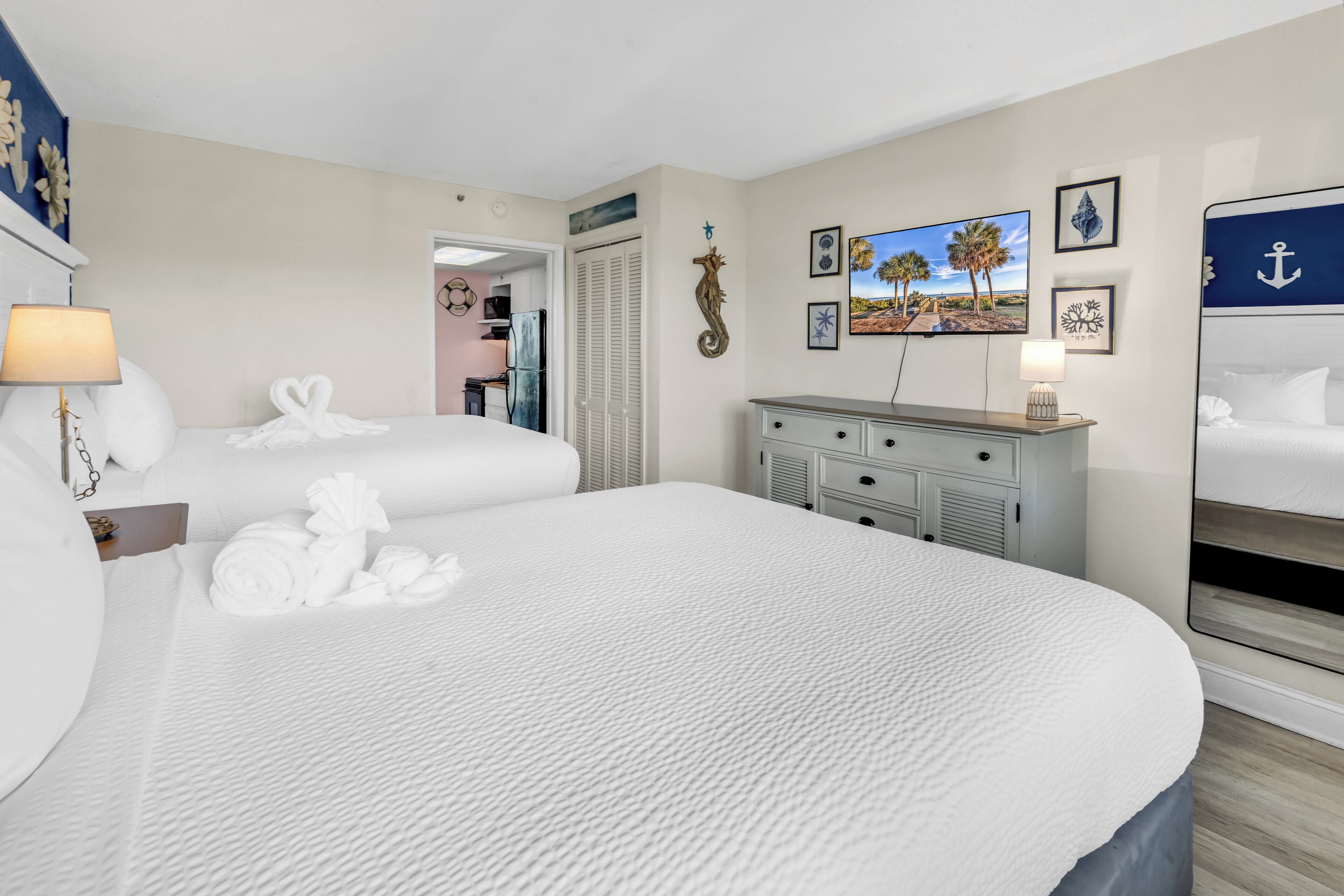 Una habitación de hotel con una cama grande, un escritorio, un aparador y un espejo.