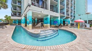 A hotel with a swimming pool, multiple balconies, and a view of the ocean. - Compass Cove Condos (Myrtle Beach)