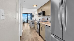A modern kitchen with stainless steel appliances, wooden cabinets, and a view to the outside. - Compass Cove Condos (Myrtle Beach)