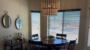 A dining area with a round table, chairs, a hanging light fixture, and two wall-mounted mirrors.