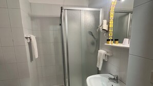 Ein modernes Badezimmer mit Duschkabine aus Glas, einem weißen Waschbecken und einer Toilette.