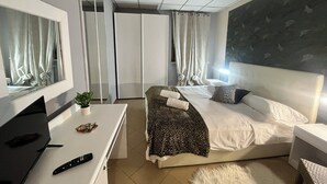 Ein modernes Hotelzimmer mit einem großen Bett, einem Schreibtisch mit einem Laptop und einem Fernseher.