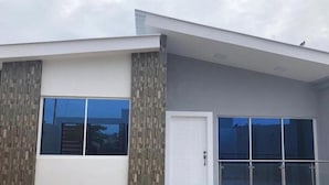 A modern building with a flat roof, large windows, and a door with a glass panel.